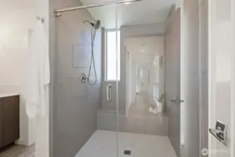 Primary suite bathroom with frameless shower door, tile bench and timeless style.