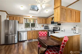 Bright kitchen features a skylight, warm cabinetry, stainless steel appliances, and a casual eat-in space for daily meals.