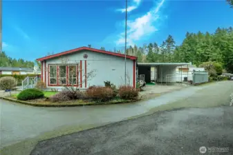 Exterior view highlights the home’s corner-lot setting with fenced yard and gated carport for added privacy and convenience.