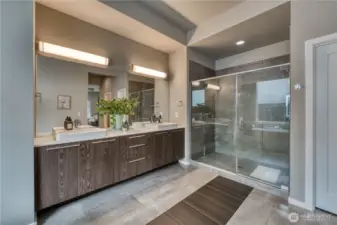 Primary bath has a classic sleek design with quarts counter and tile floor and shower surround.