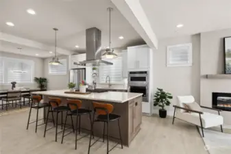 The kitchen is at the heart of the home featuring a large island with seating, pendant lights, a 5-burner gas cooktop with extraction hood, and thick slab quartz countertops.  The family room and dining room are flanked on both sides of the kitchen.