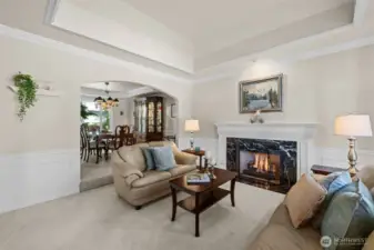 Coffered ceiling over formal living room, extensive mill work package, and natural gas fireplace with intricate wood wrapped mantel.
