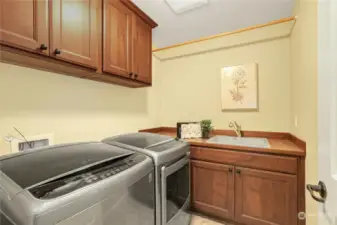 Upper level laundry room with side-by-side washer and dryer, utility sink and plenty of storage.