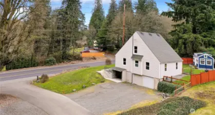 Drone view of side of property. Driveway meets private side road. Detached blue structure to your right.