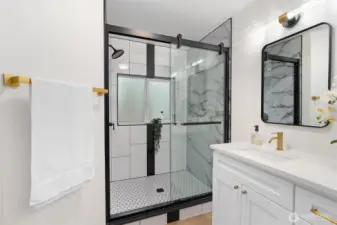 Frameless glass, matte black finishes, and marble-inspired tile create a spa moment worth lingering in.