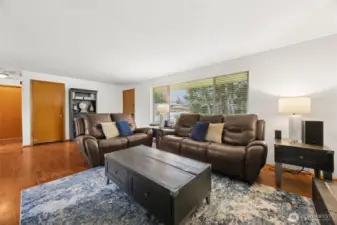 Bright open living area makes this room feel welcoming- large window & hardwood flooring.