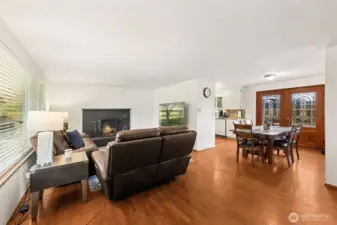 View looking from the front door over the warm family room, dining area and a peak into the kitchen. Double doors lead to a nice spacious backyard patio.