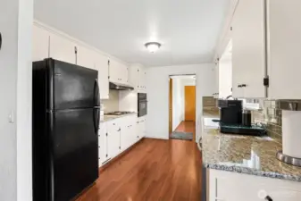The classic white galley kitchen has been refreshed with granite countertops and a neutral subway tile backsplash.