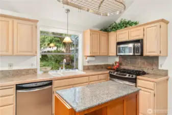 Spacious kitchen has stainless appliances, gas range, granite tiled counters and hardwood flooring...