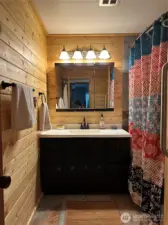 Guest bath with pine walls and tile floors include a tub shower.