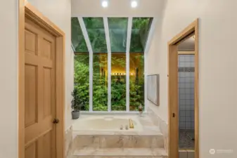 Luxurious primary bath features tall ceilings and a romantic soaking tub looking out to tranquility.
