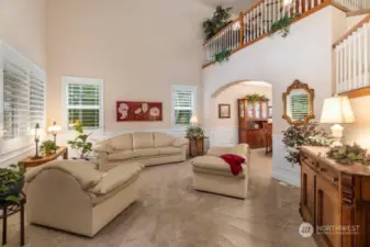 The living room with its beautiful cathedral ceiling. The window shutters throughout the home add a classic touch.