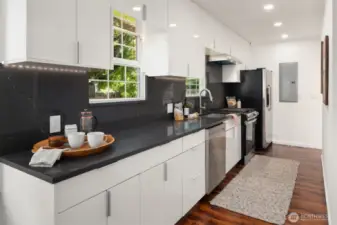 Sleek cabinets with solid quartz counters and a solid quartz backsplash. The updated electrical panel is at the end of the kitchen.