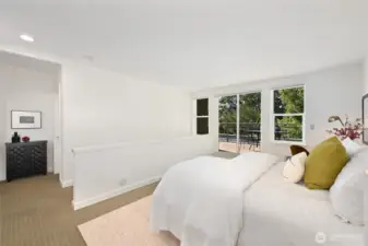 The secondary bedroom on the upper level is expansive. The full bathroom on this level is to the left of the black cabinet. The primary bedroom is to the right of it.