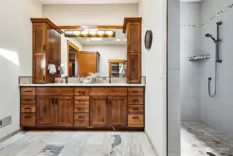 The luxurious primary ensuite blends functionality with opulence, boasting a beautiful double vanity, heated tile flooring, and spa-like walk-in tile shower.