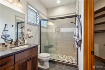 Ensuring a comfortable stay, the private ensuite off the guest/junior suite is well-appointed with its slab counters, tile shower, & custom designed walk-in closet.