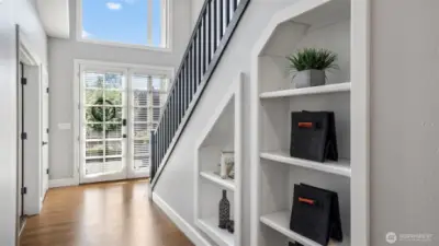 Customizable glass doors with built-in blinds lead you into a bright entryway with rich hardwood flooring. Functional cubbies line the stairs, ideal for showcasing personal touches or keeping essentials organized