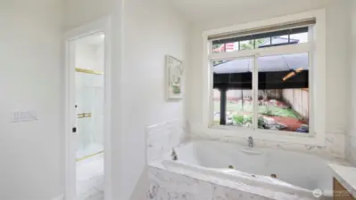 The en suite bathroom offers a spacious walk-in shower and separate toilet, a large soaking tub, and a huge window overlooking the backyard.
