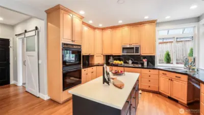 Both the pantry and laundry room feature stylish barn slider doors, conveniently located beside the kitchen, which boasts a double oven and tall cabinetry for added storage and functionality