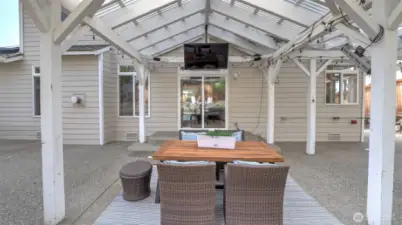 A large covered area welcomes you as you step outside, complete with a table and a cozy relaxation spot. Decorative lights enhance the ambiance, and there’s plenty of space to add a screen, TV, or projector for extra entertainment!