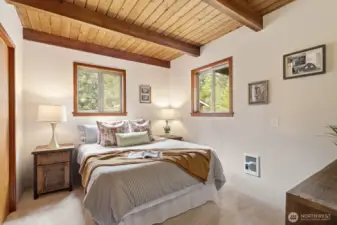 Spacious main-floor bedroom with wood-planked ceilings, exposed beams, and a generous closet.