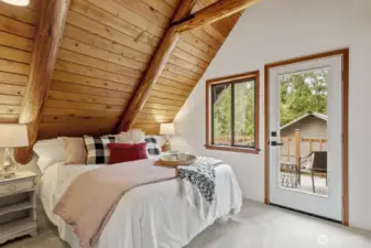 Spacious upstairs bedroom with vaulted wood-planked ceilings and direct access to the upper deck.