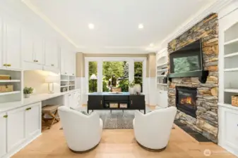 Luxury office retreat w/ designer built-ins, statement stone fireplace, & front yard views.