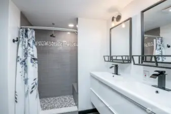 Fully tiled shower in primary bathroom with rain shower head