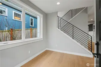 As you step inside, a serene neutral palette, expansive windows, and warm-toned floors create an inviting introduction to the home’s modern design.