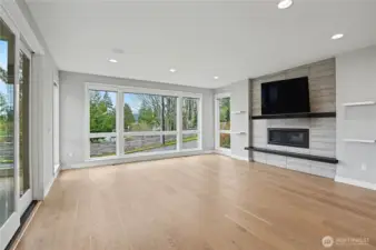 Anchored by a modern fireplace, the living room showcases floor-to-ceiling windows, recessed lighting, and effortless access to the patio.