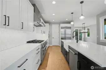 The chef’s kitchen pairs stainless steel appliances with sleek countertops, striking dual-toned cabinetry, and generous pantry storage.