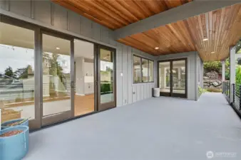 Entertain in style on this covered patio with rich wood-plank ceilings, integrated recessed lighting, and contemporary railing for seamless indoor-outdoor living.