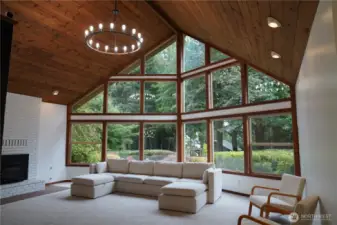 The living room is a stunner and offers a cozy ambiance, featuring a large cathedral ceiling, chandelier, and wood-burning fireplace insert. Enjoy a beautiful view to the garden outside.