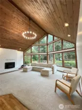 The living room is a stunner and offers a cozy ambiance, featuring a large cathedral ceiling, chandelier, and wood-burning fireplace insert. Enjoy a beautiful view to the garden outside.