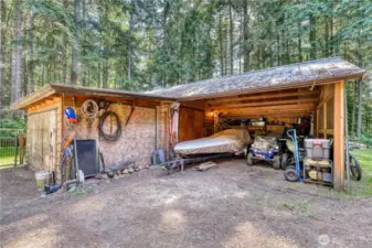 Detached carport for 2 cars with attached shop space.