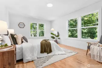 Gigantic main level primary bedroom with large picture windows overlooking the greenspace and creek below it.