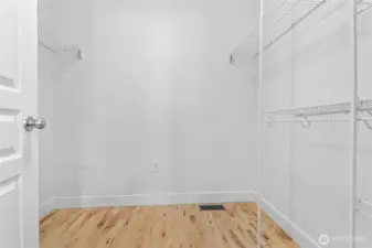 Sizable walk-in closet with attached shelving and hanging rods.
