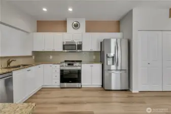 Big kitchen with white cabinets, granite, stainless steel appliances, tile backsplash, & new laminate floors