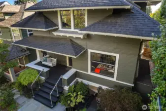 Front yard porch has swinging bench and large patio with basketball hoop and seating area