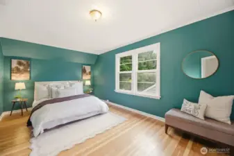 Large, beautiful primary bedroom with original hardwood flooring.