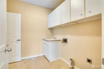 Take the hall straight back from the front door to this laundry room with a utility sink and cabinets for storage.