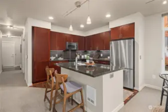 Open concept kitchen has an eat-in bar, granite counter tops, cherry cabinets and modern stainless appliances.