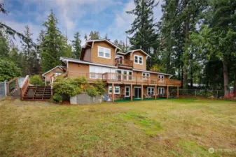 View of the home and decks from the water.  Large fenced yard.