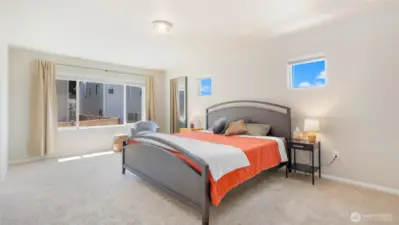 The primary suite is so spacious! Yes that's a king-sized bed, and the two high windows look west for optimal afternoon light.