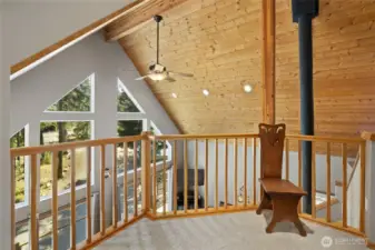 The loft looks out over the great room, highlighting the tall ceilings, wood beams, and tongue and groove detailing.