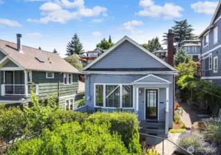 Light, bright & above it all this 1906 Craftsman features a light-filled open concept tastefully updated to contemporary standards. 3 bedrooms & 2 baths on a lushly landscaped lot with an unobstructed view from a wall of western windows to the Olympics & partial Elliott Bay views. Gorgeous hardwood floors throughout complement the period detail of mantled fireplace & built-in bookcases typical of this vintage. The thoughtful 3 point plan of range-frig-sink will save steps.There is ample prep, cupboard & cabinet space here to please the chef. The primary bedroom & bath sits quietly at the back of the house looking out over the gardens, with two more guest bedrooms serving as office or daybed. One car garage too. Here you'll enjoy outdoor living all summer long!
