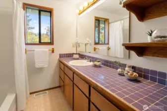 A bright main floor bathroom with generous counter space and a wide window that brings in natural light.