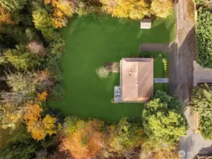 An aerial view reveals the full half acre bordered by mature trees and adjacent to a two acre wetland offering rare privacy and a close connection to nature.