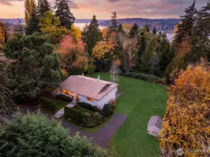 At dusk the home rests in a quiet clearing above its half acre while the shimmer of Lake Washington nearby signals easy access to beaches, trails and all the shoreline offers.