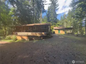 Large, covered wood storage next to large outbuilding.